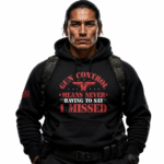 A high-fidelity studio shot of the Gildan 18500 Heavy Blend hooded sweatshirt featuring the bold 'Gun Control Means Never Having to Say I Missed' graphic. The 8.0 oz medium-heavy fabric is presented on a rugged dark slate surface under crisp lighting, highlighting the tubular knit construction and spacious kangaroo pouch.
